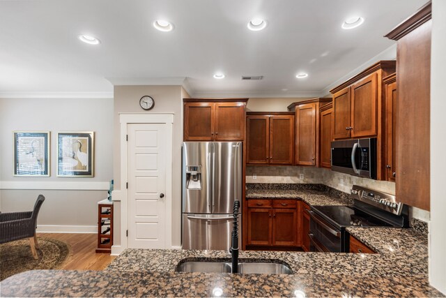 kitchen with dark stone counters, light hardwood / wood-style flooring, sink, crown molding, and stainless steel appliances