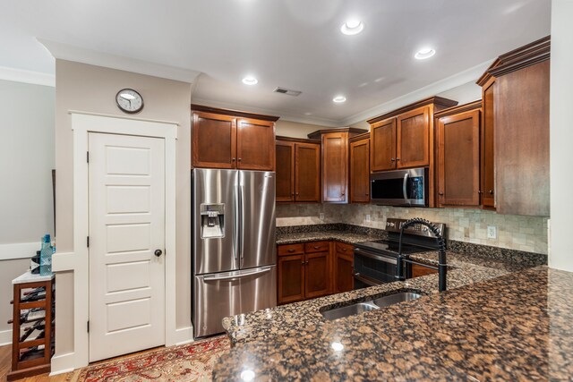 kitchen featuring decorative backsplash, appliances with stainless steel finishes, crown molding, and dark stone countertops