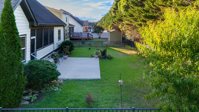 view of yard featuring a storage unit, a deck, and a patio area