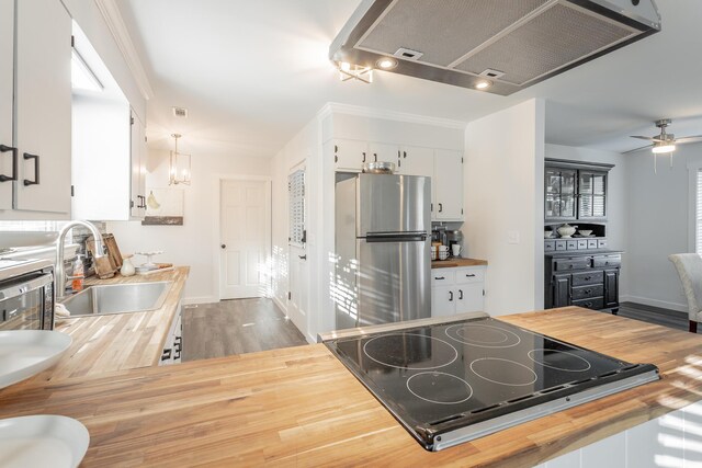 kitchen featuring ceiling fan, white cabinetry, ventilation hood, stainless steel refrigerator, and black cooktop