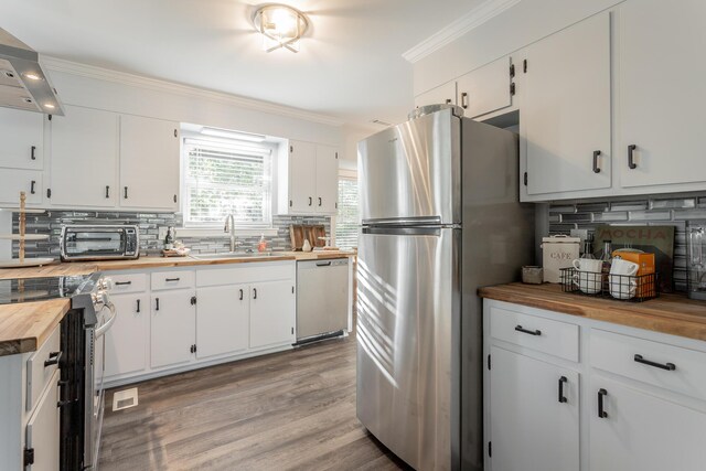 kitchen featuring white cabinets, appliances with stainless steel finishes, wood counters, and sink