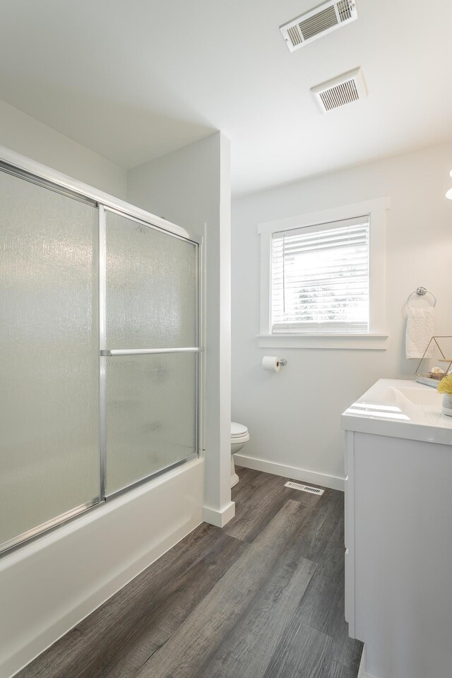 full bathroom with enclosed tub / shower combo, vanity, toilet, and hardwood / wood-style flooring