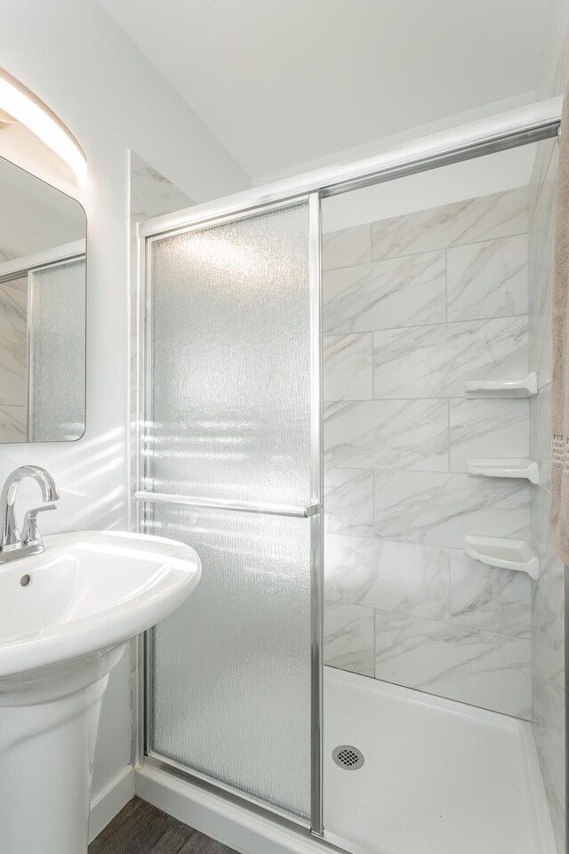 bathroom with wood-type flooring, a shower with door, and sink