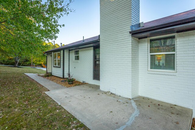 view of side of property featuring a lawn and a patio