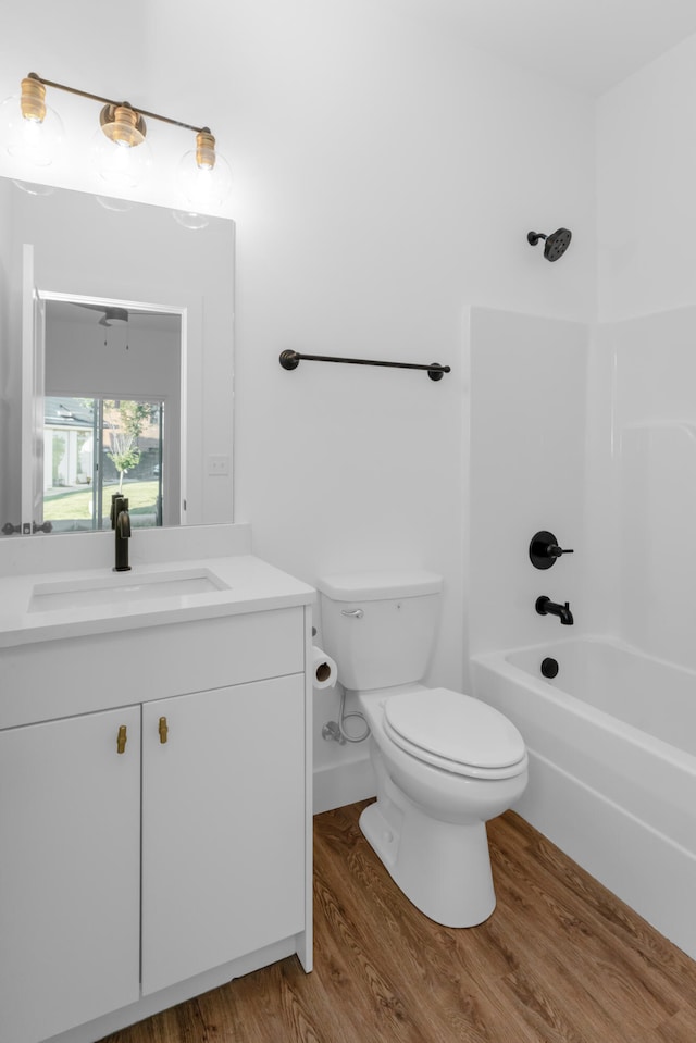 full bathroom featuring wood-type flooring,  shower combination, vanity, and toilet