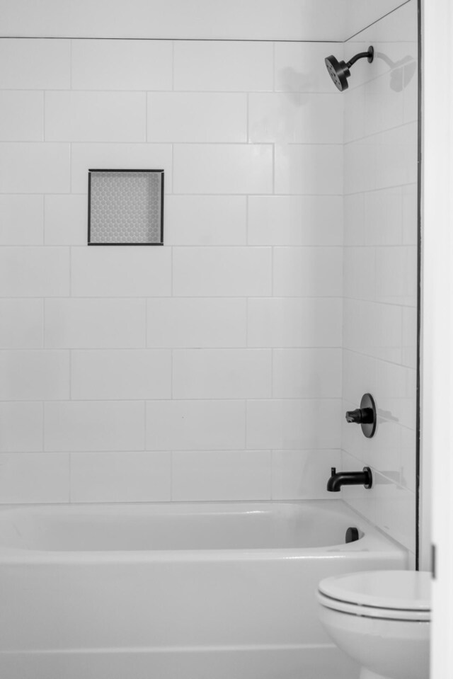 bathroom with tiled shower / bath combo and toilet