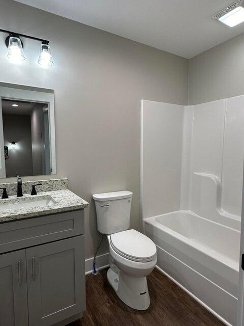full bathroom featuring shower / bathing tub combination, toilet, vanity, and hardwood / wood-style flooring
