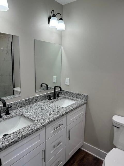 bathroom with vanity, toilet, wood-type flooring, and a shower
