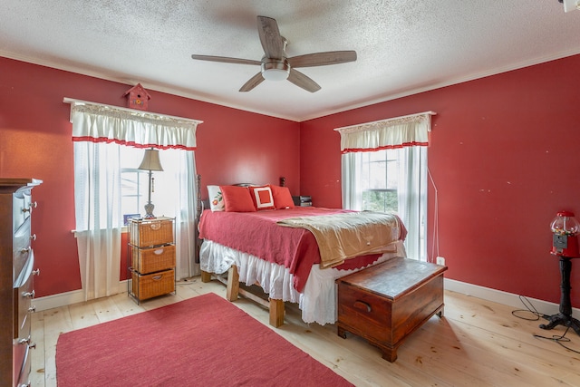 bedroom with a textured ceiling, ceiling fan, and light hardwood / wood-style flooring