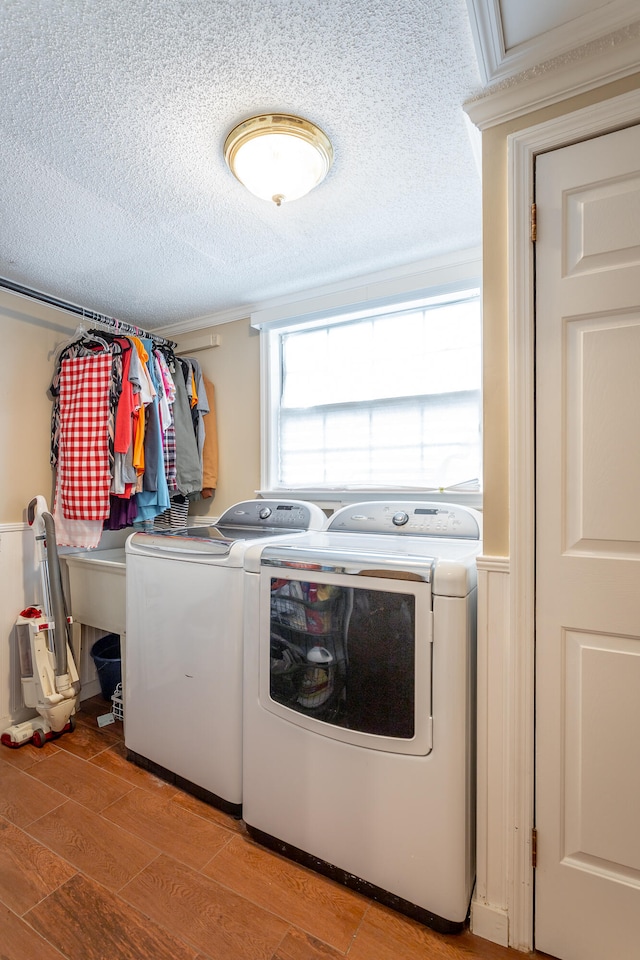 washroom featuring light wood-type flooring, washer and clothes dryer, and a textured ceiling