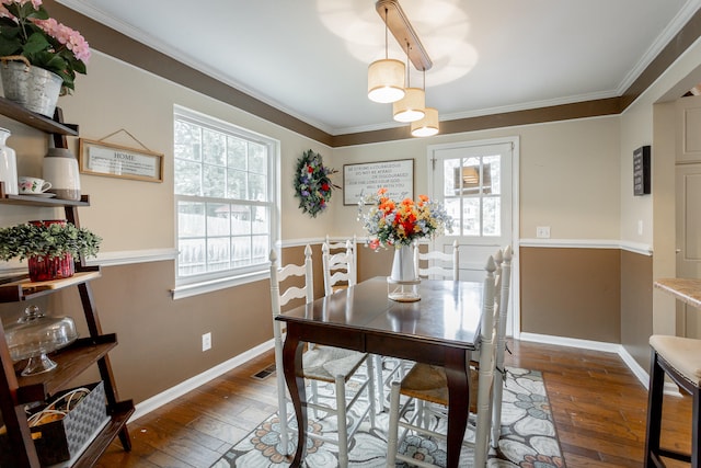 dining space featuring dark hardwood / wood-style floors, ornamental molding, and a healthy amount of sunlight