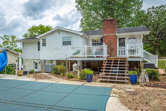 rear view of house with central air condition unit and a swimming pool side deck