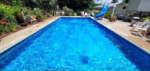 view of swimming pool with a water slide and a patio