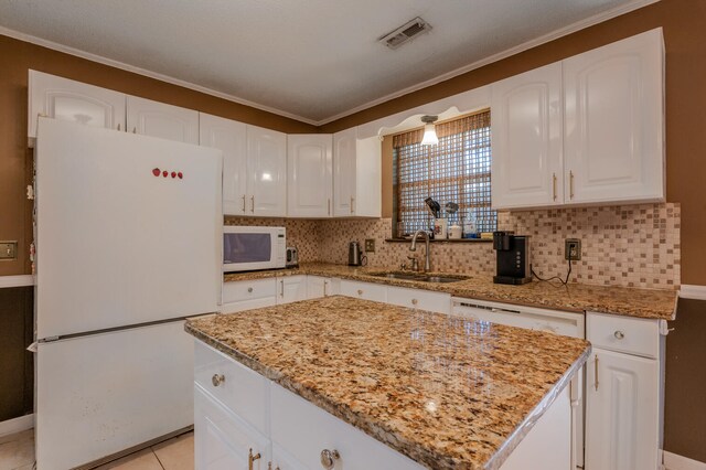 kitchen with white appliances, white cabinets, sink, and a center island