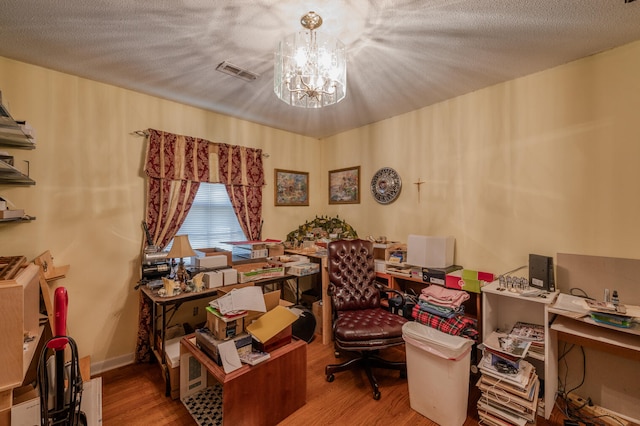 office featuring light wood-type flooring, a notable chandelier, and a textured ceiling