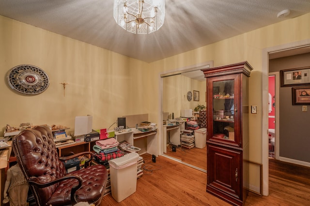 home office featuring a notable chandelier, hardwood / wood-style flooring, and a textured ceiling