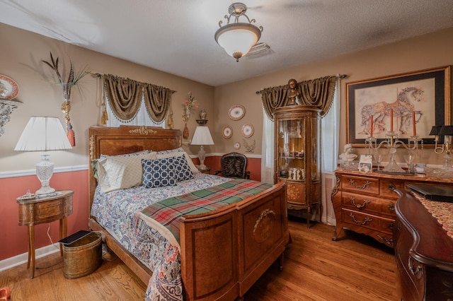 bedroom featuring a textured ceiling and light hardwood / wood-style flooring