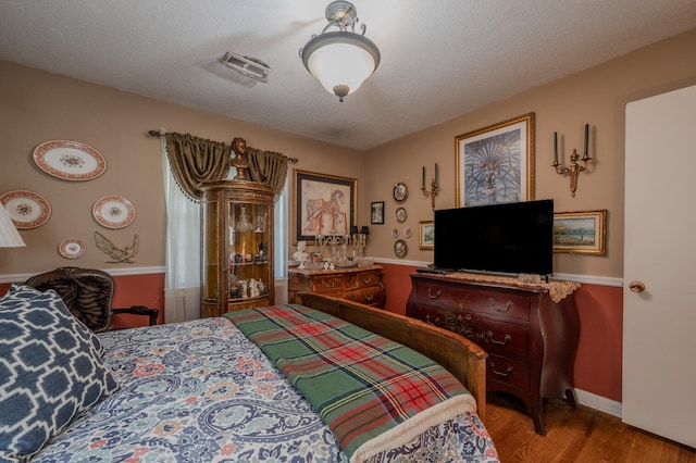 bedroom with a textured ceiling and light hardwood / wood-style floors