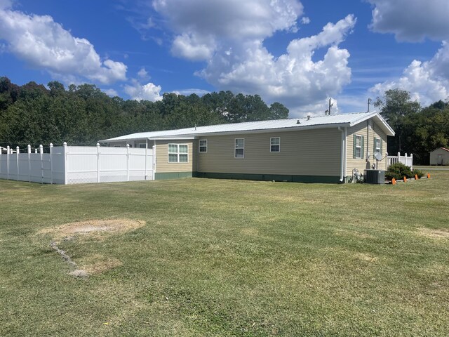 rear view of house with a lawn and central AC