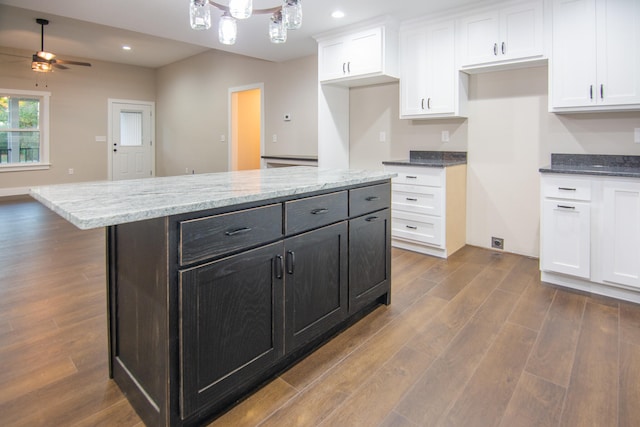 kitchen with white cabinetry, hardwood / wood-style flooring, ceiling fan, light stone counters, and a center island