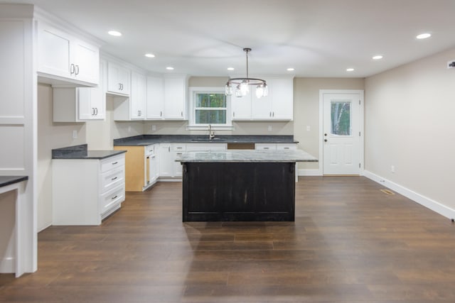 kitchen featuring decorative light fixtures, a center island, white cabinetry, and sink