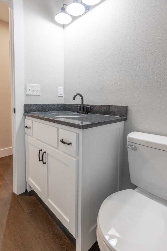 bathroom featuring toilet, wood-type flooring, and vanity