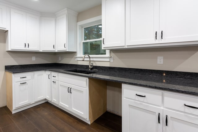 kitchen featuring white cabinets, dark stone counters, and sink