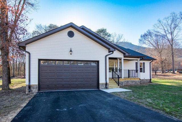 view of front of property featuring covered porch, a garage, a mountain view, and a front lawn