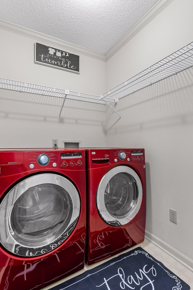 washroom with a textured ceiling, washing machine and dryer, and ornamental molding