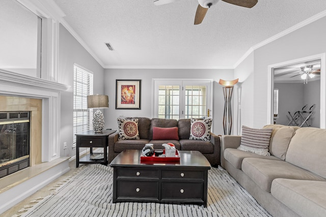 living room with ornamental molding, lofted ceiling, a premium fireplace, and ceiling fan