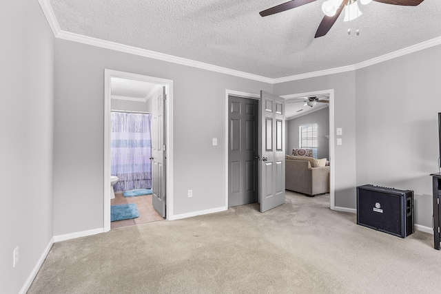 unfurnished bedroom featuring ceiling fan, ornamental molding, a textured ceiling, light colored carpet, and ensuite bathroom