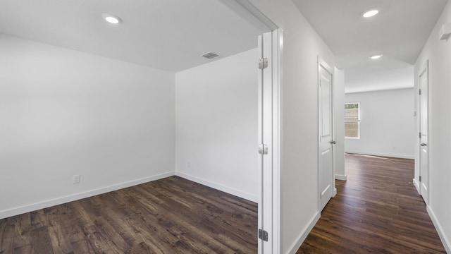 corridor featuring dark wood-style floors, visible vents, recessed lighting, and baseboards