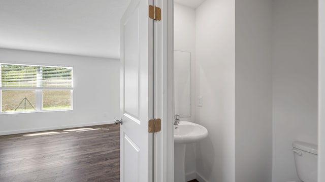 bathroom with toilet, wood finished floors, and baseboards