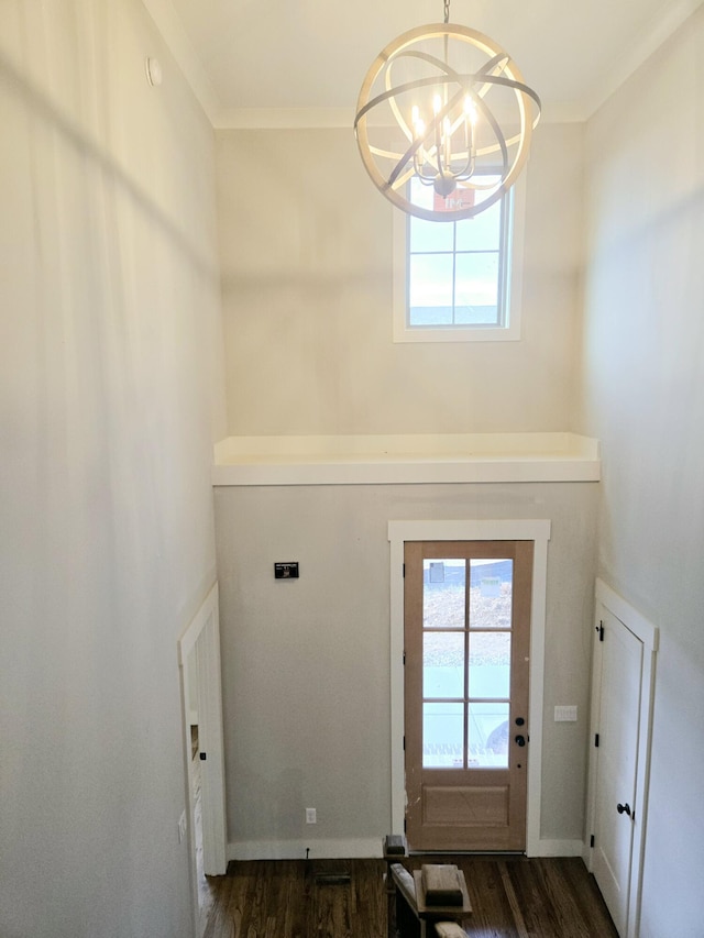 entryway with an inviting chandelier, crown molding, baseboards, and dark wood-style flooring