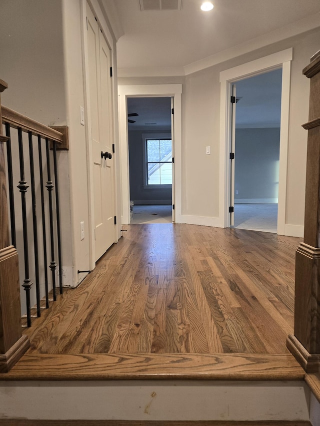 hall with stairway, visible vents, baseboards, and wood finished floors