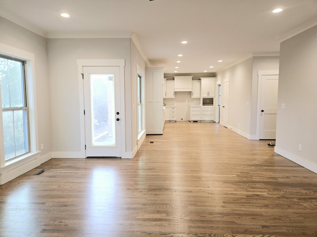 unfurnished living room featuring baseboards, ornamental molding, wood finished floors, and recessed lighting