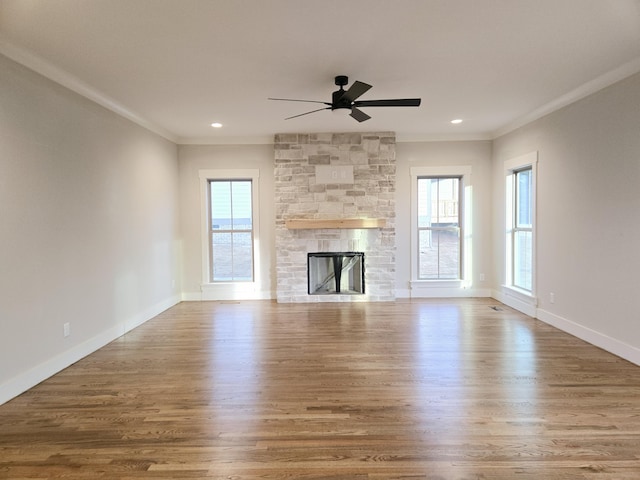 unfurnished living room with a fireplace, wood finished floors, a wealth of natural light, and crown molding