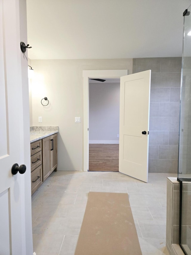 full bath with tile patterned flooring, a tile shower, and vanity