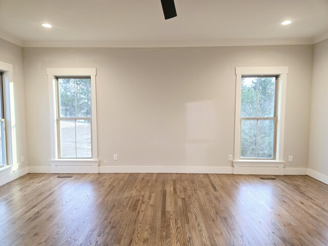 empty room with baseboards, ornamental molding, a wealth of natural light, and wood finished floors