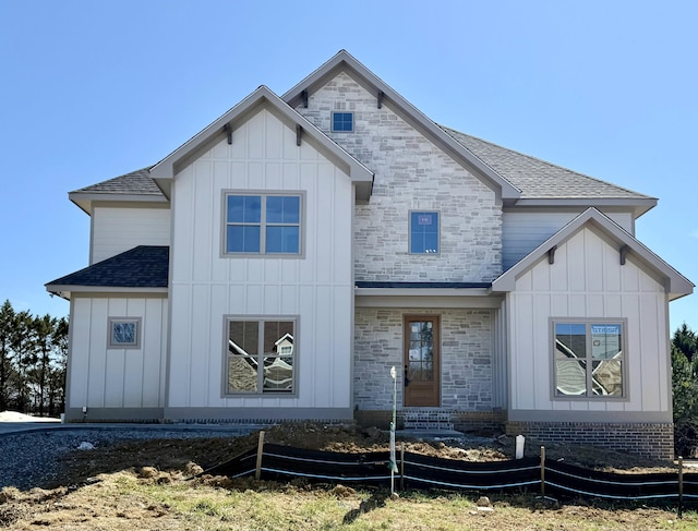 modern farmhouse featuring stone siding, board and batten siding, and roof with shingles