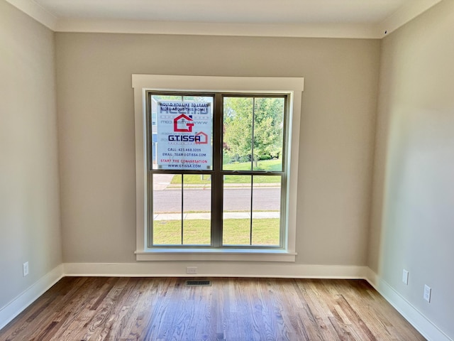 unfurnished room with visible vents, baseboards, and wood finished floors