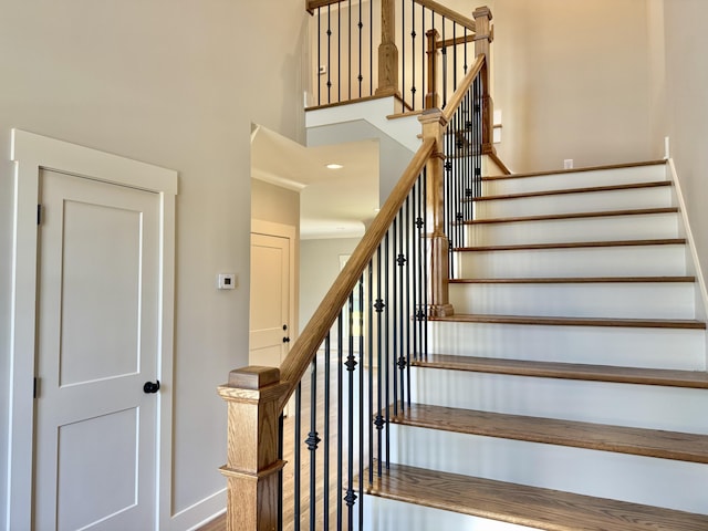 stairway featuring baseboards and a high ceiling