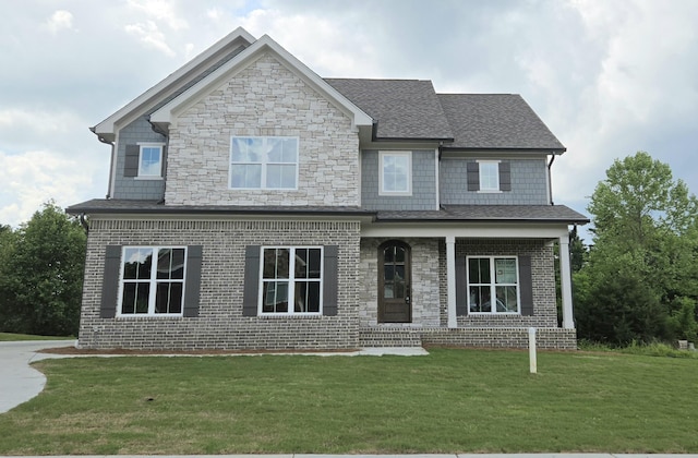 view of front facade with covered porch, stone siding, and a front yard