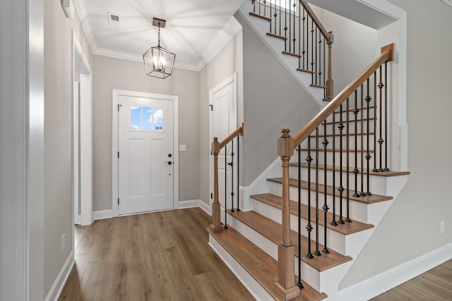 foyer entrance featuring crown molding, hardwood / wood-style flooring, and a chandelier