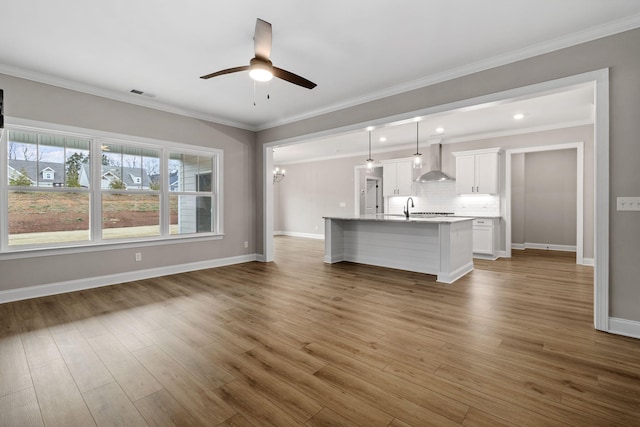 unfurnished living room featuring crown molding, sink, hardwood / wood-style flooring, and ceiling fan