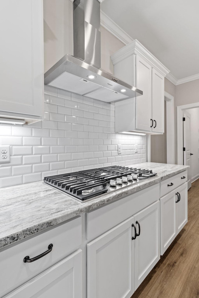 kitchen with white cabinets, extractor fan, tasteful backsplash, ornamental molding, and stainless steel gas cooktop