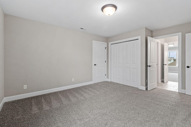 unfurnished bedroom featuring light carpet and a closet