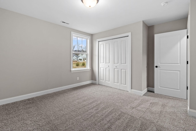 unfurnished bedroom with a closet and light colored carpet