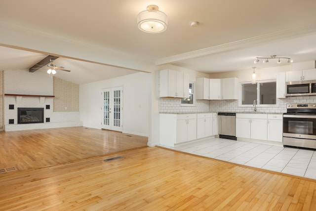 kitchen featuring white cabinets, stainless steel appliances, backsplash, and light hardwood / wood-style flooring