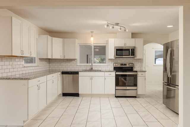 kitchen with white cabinetry, light stone counters, backsplash, stainless steel appliances, and sink